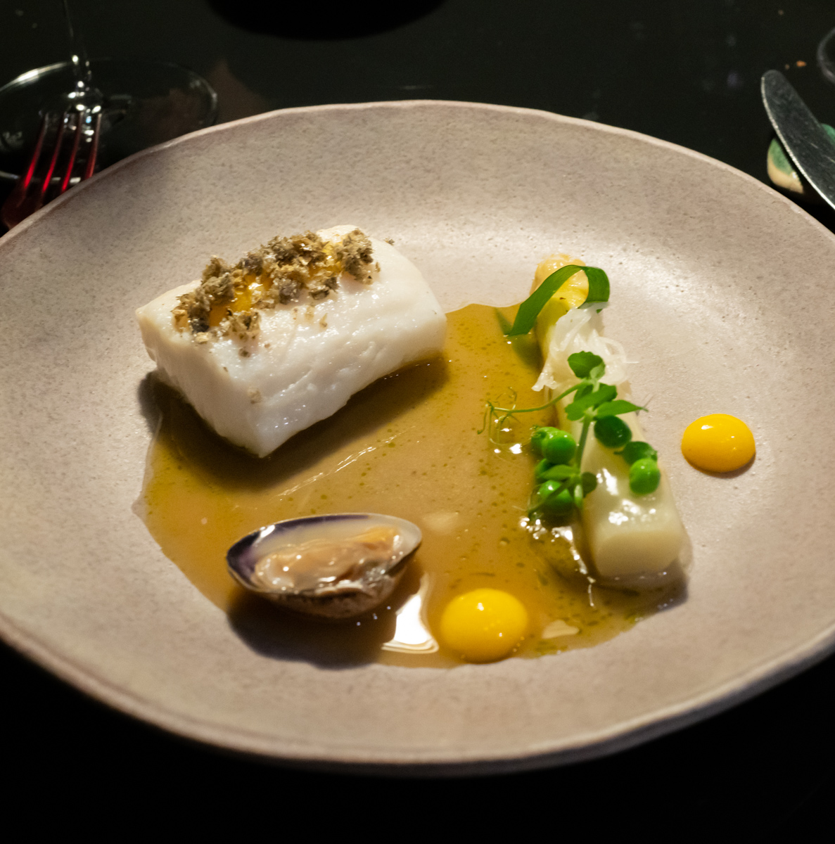 The seafood course consisted of a simple piece of hake topped with “crunchies” made from the skin (removed and deep fried). This came with a beautiful piece of white asparagus (which was in season at the time), peas, and a sauce made from fish essence and egg. On the side, dollops of “egg yolk“ completed the plate.